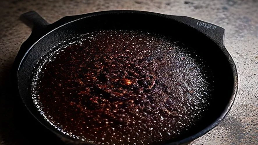 Cast iron skillet showing greasy and burnt areas requiring different cleaning methods