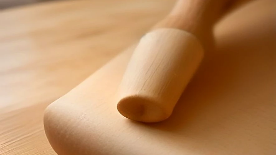Dough being rolled on a silicone mat next to a wooden pastry board