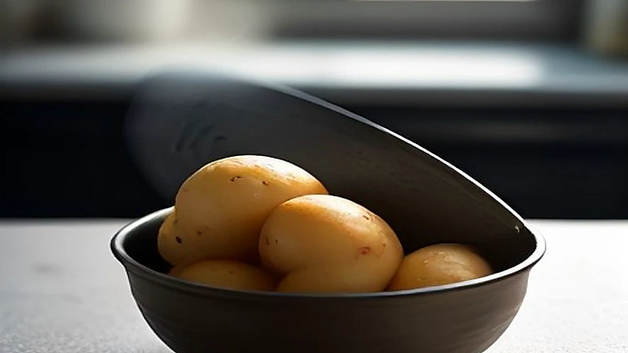 Using a potato ricer to press cooked potatoes into a bowl