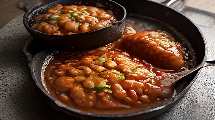 sauté pan containing a simmering sauce and skillet with seared steak
