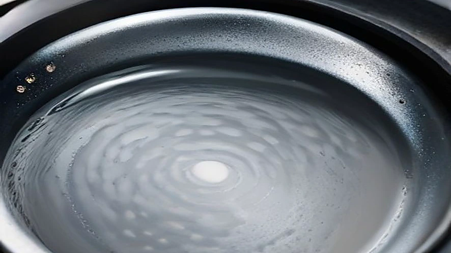 Condensation droplets on underside of stainless steel pan lid during frying