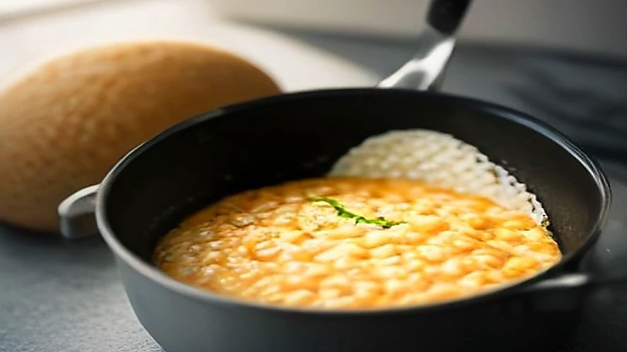 Close-up showing the curved interior walls of a saucier pan facilitating stirring risotto