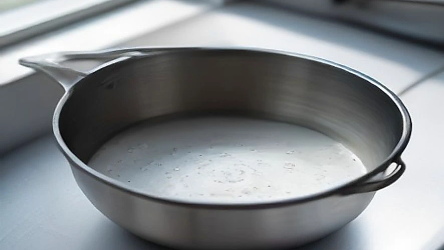 Cross-section of milk pan base revealing layered construction for heat distribution