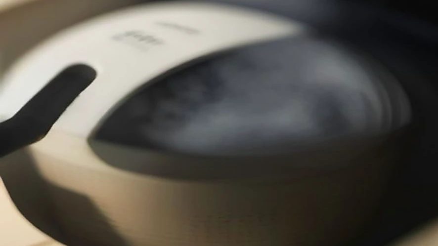 Glass oil sprayer producing fine mist over air fryer basket