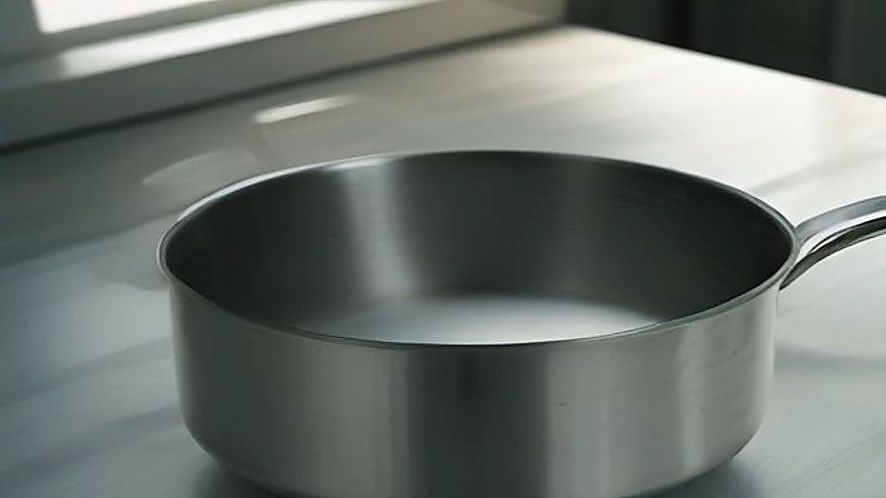 Tri-ply stainless steel saucepan showing layered base and ergonomic handle design